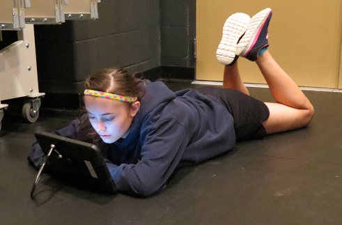 Hannah Singewald makes use of her tablet during a break in musical rehearsals