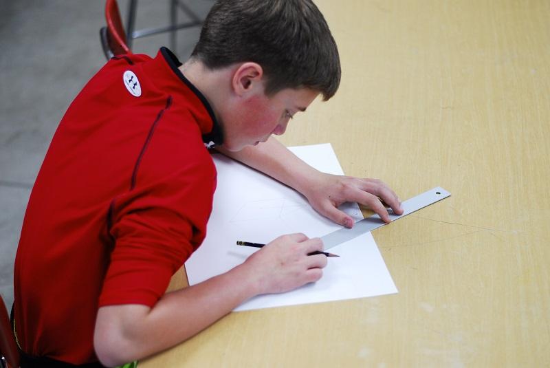 Using a ruler, a student practices his perspective techniques.