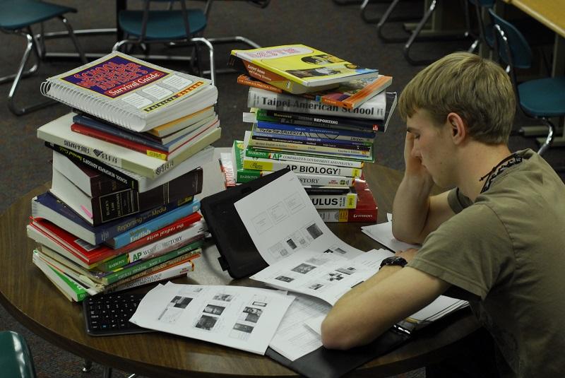 Looking overwhelmed by stack of books and homework, junior James Watson demonstrates the intense preparation for the upcoming finals.