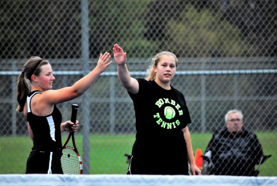 Senior Taylor Jackson and junior Paige Meist high-fiving after scoring a point.