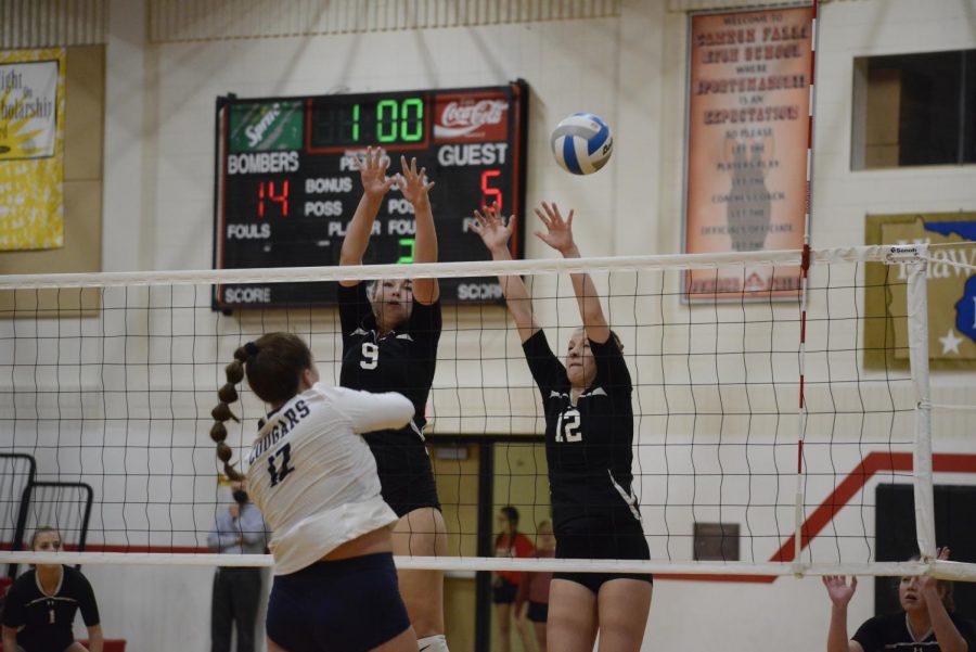 Two varsity players attempt to block an incoming hit from the Zumbrota-Mazeppa Cougars.