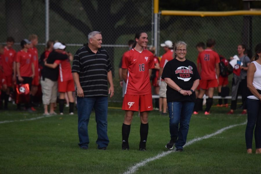 Mitch Hoffman and his parents meet at midfield as the senior soccer players are honored
