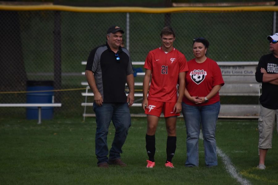 Connor Loeschke is flanked by his parents at midfield as an honored senior