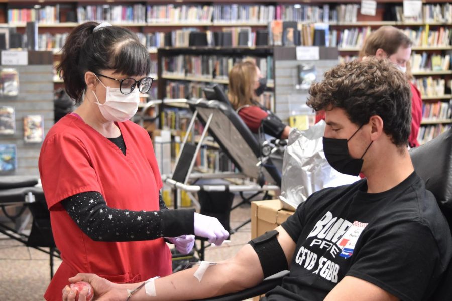 A staff member checks in while Riley Buchheit donates blood. 
