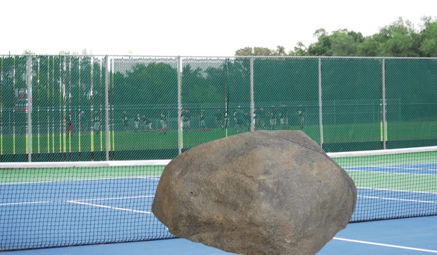 A large rock, previously located in front of the school building, has made its way to the tennis courts.