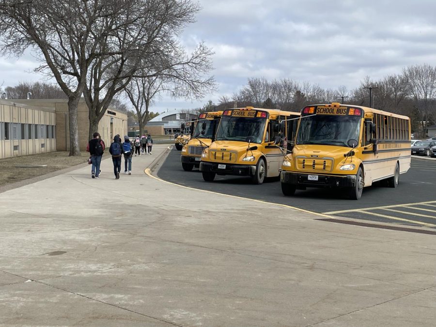 School buses, and the drivers inside, line up to take students home after school.