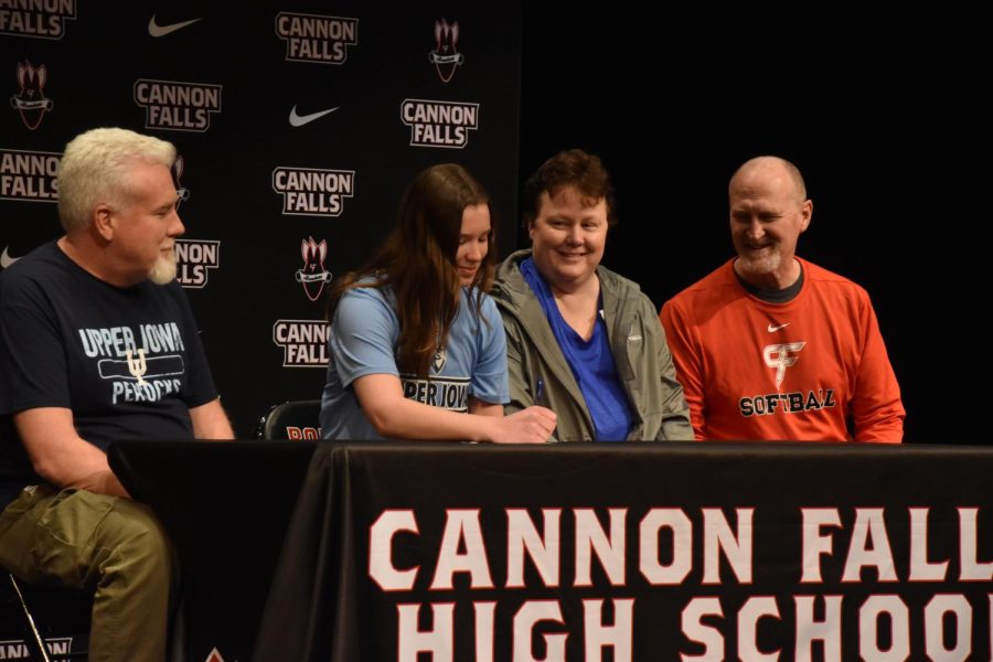 With+her+parents+and+coach+by+her+side%2C+Abby+Breuer+signs+a+softball+commitment.+