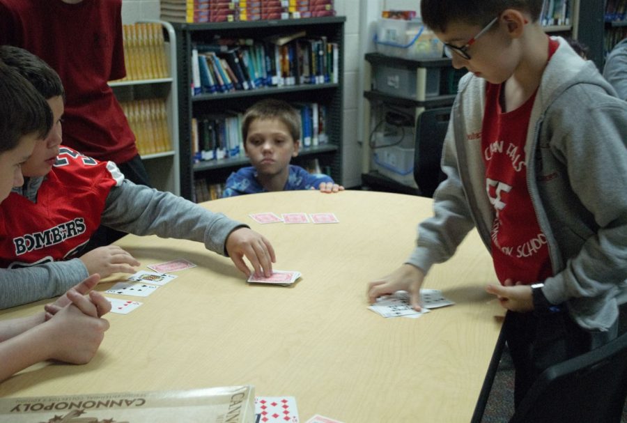 A group of sixth grades play a competitive game of cards in Ms. Ottos room.