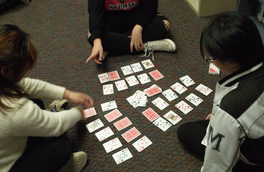 A game of cards is played by three eighth graders.