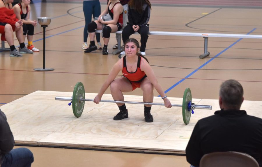 Addison Miller starts her 40-kilo lift while the judges watch attentively.  
