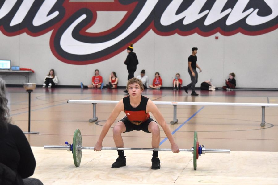 Dylan Anderson prepares to snatch 50 kilos while his teammates watch from behind.