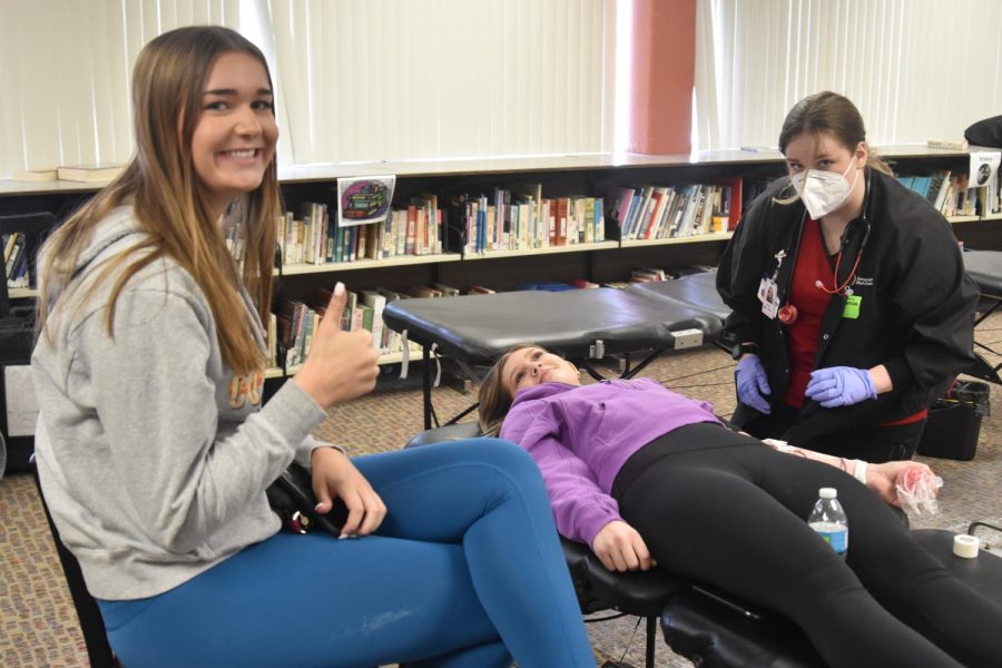 Elle Lind supports Grace Swanson as she donates blood. 