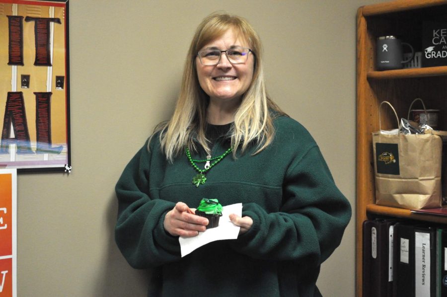 Kirsten Hoffman poses for a photo with her green sweater and festive cupcake. 