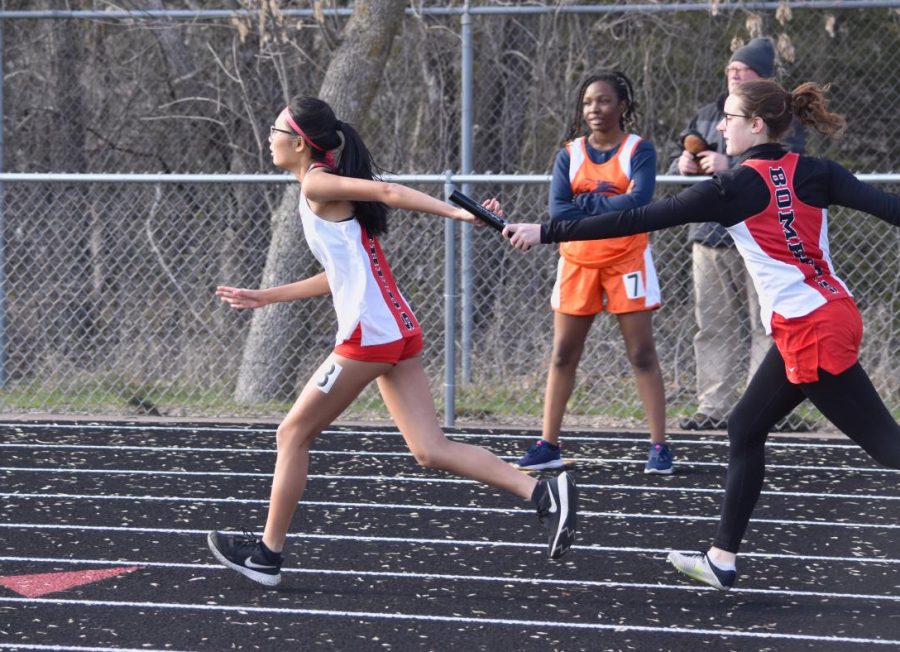 Lydia Pedersen passes a baton to Cindy Zheng during a recent track meet.