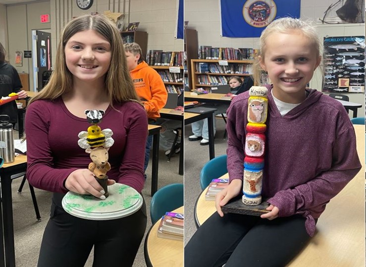 Kylie Sindt and Kinzley Rezac display the totem poles they created for reading class