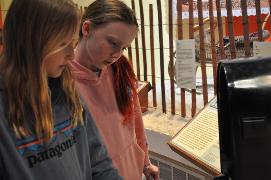 Kinzley Rezac and Anya Nygaard carefully read information for an exhibit