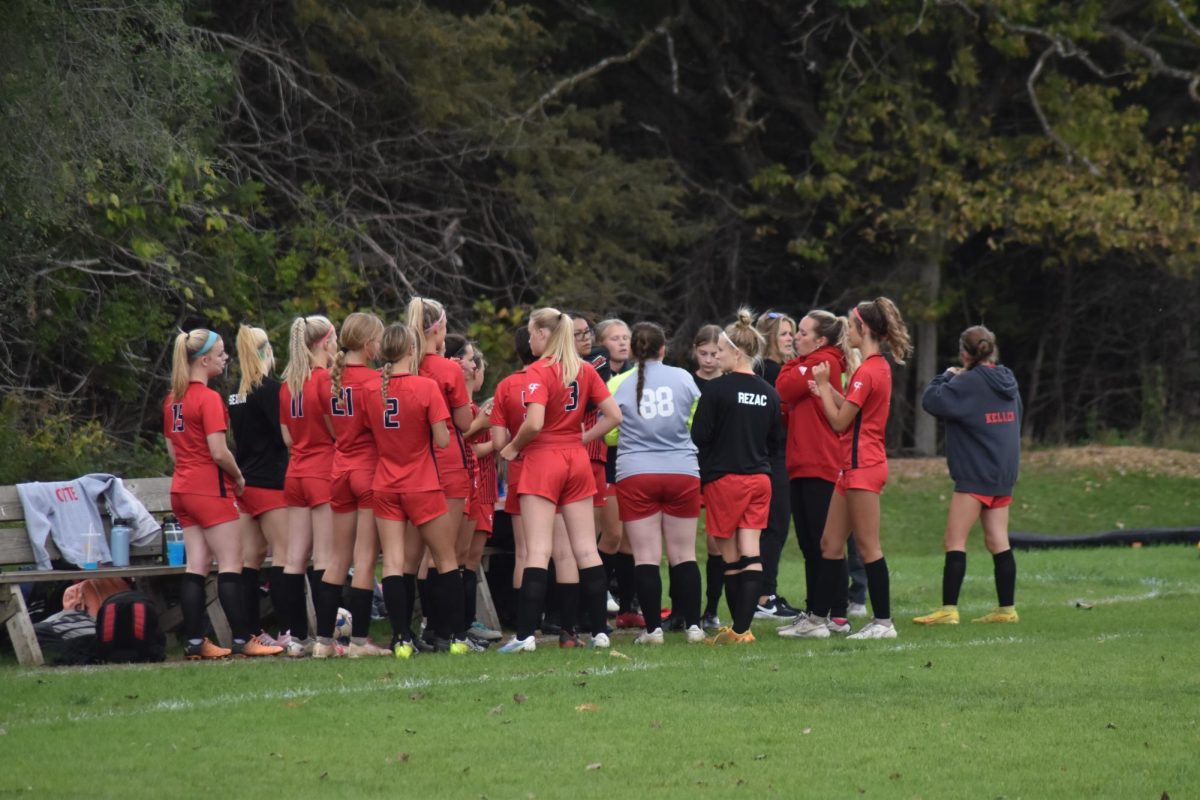 The Girls Soccer team huddles around their coach to discuss game plans.