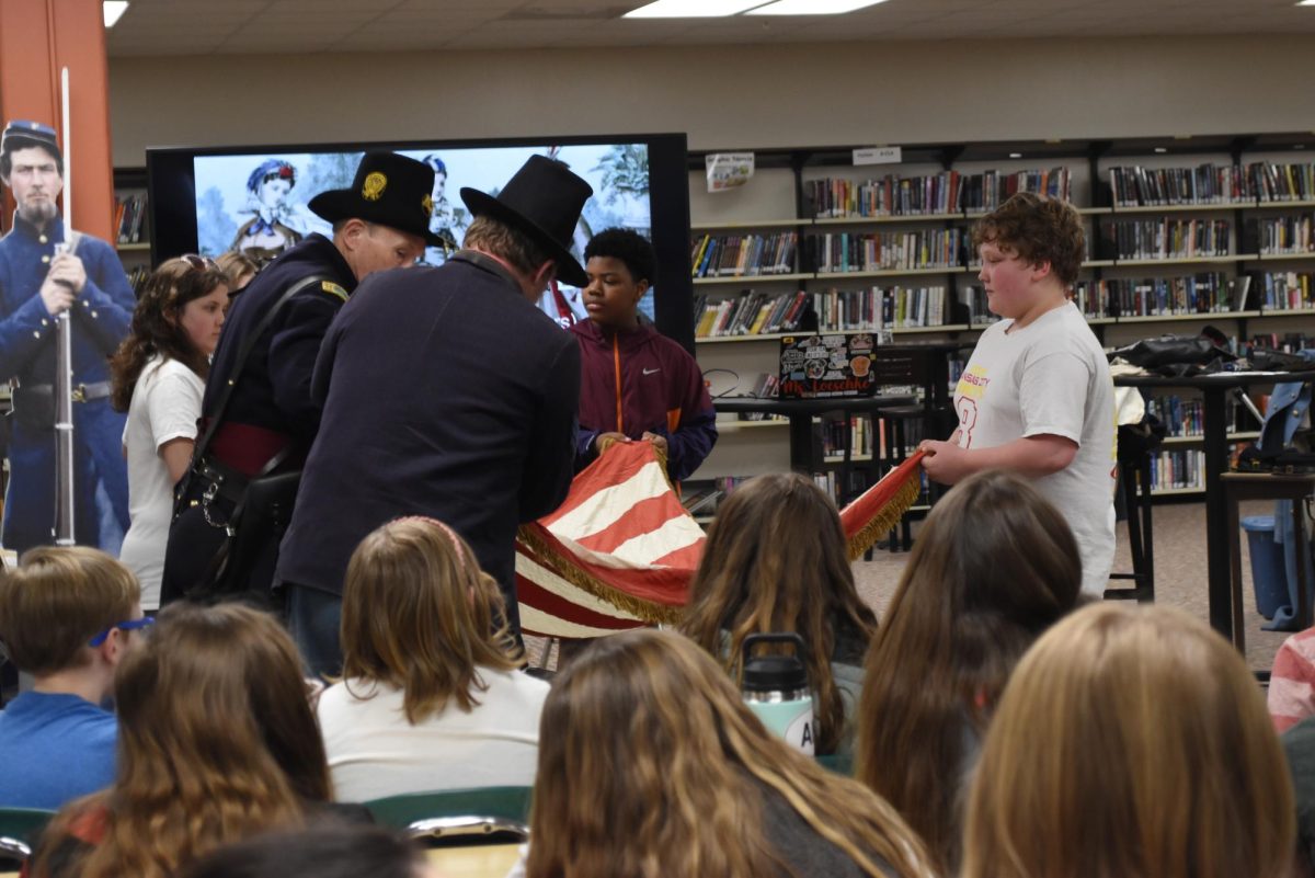 The reenactors help the boys fold up the old-timey flag.