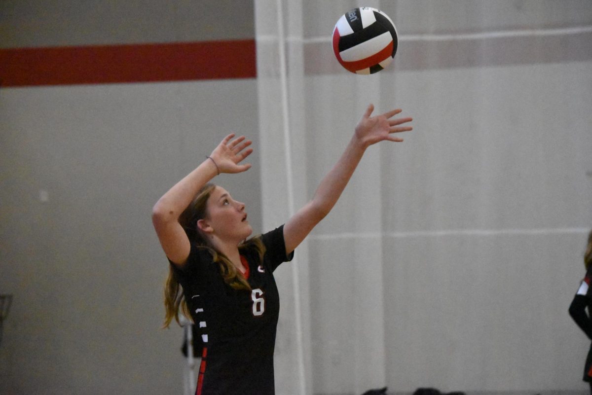 Madeline Thompson serves the ball over the net