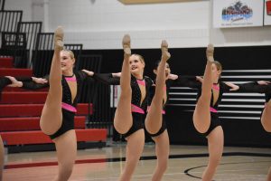 Dancers do a right open kick in a kickline.