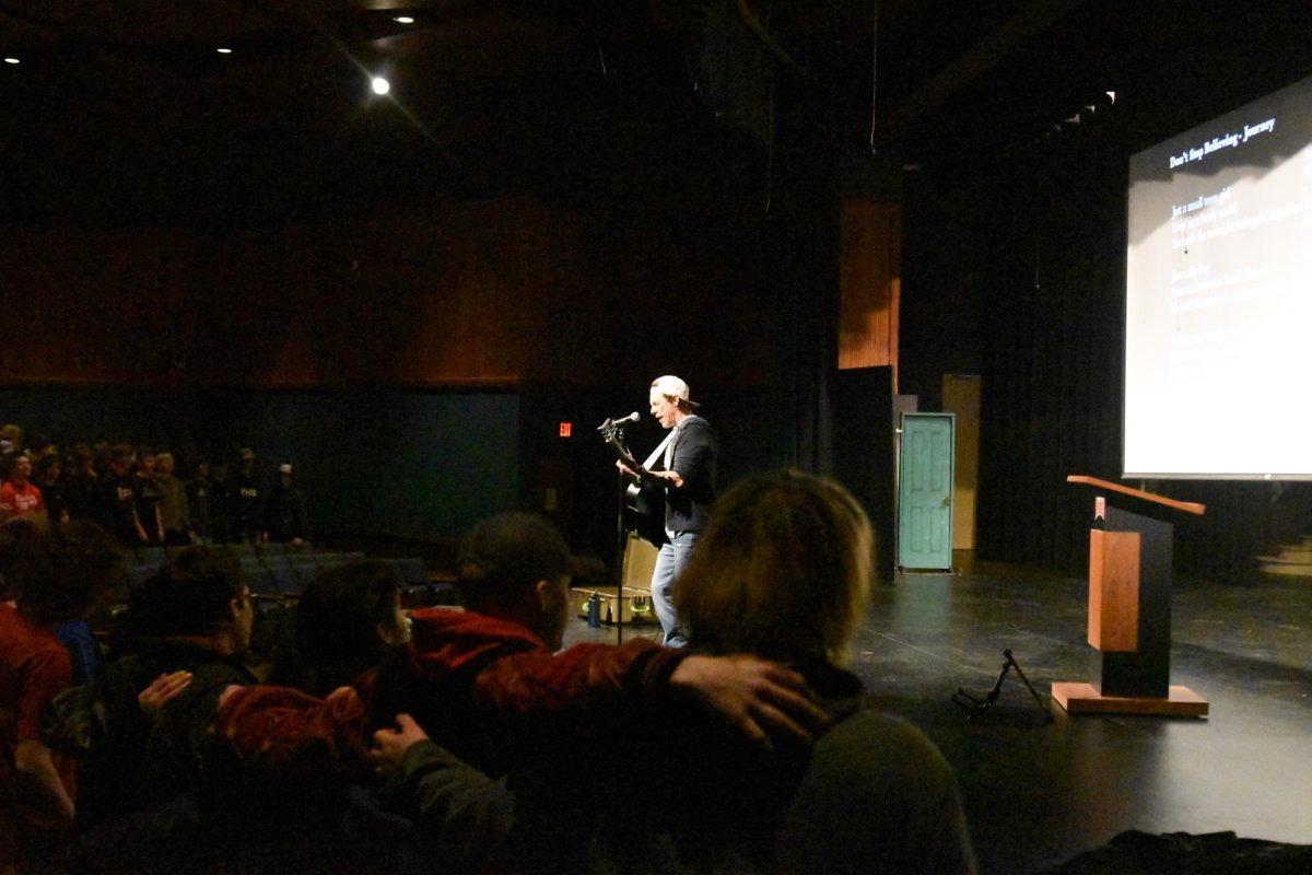 Beckman uses his guitar to aid the presentation's music aspect.