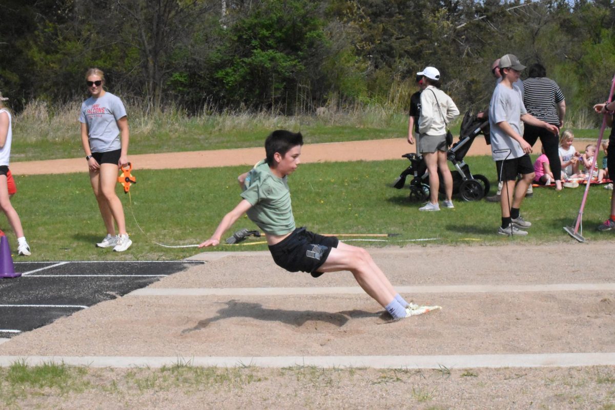 6th grader Logan Theil lands in the sand for long jump.