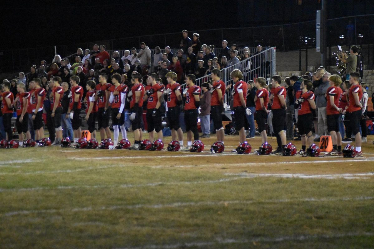 The football team salutes the flag before a game against Randolph.
