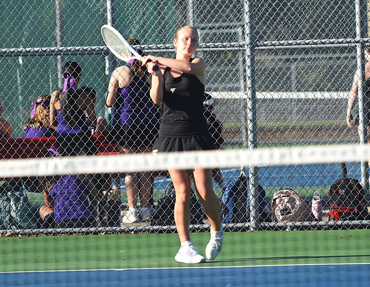Jillian Sjoquist finishes a backhand hit during her singles match.