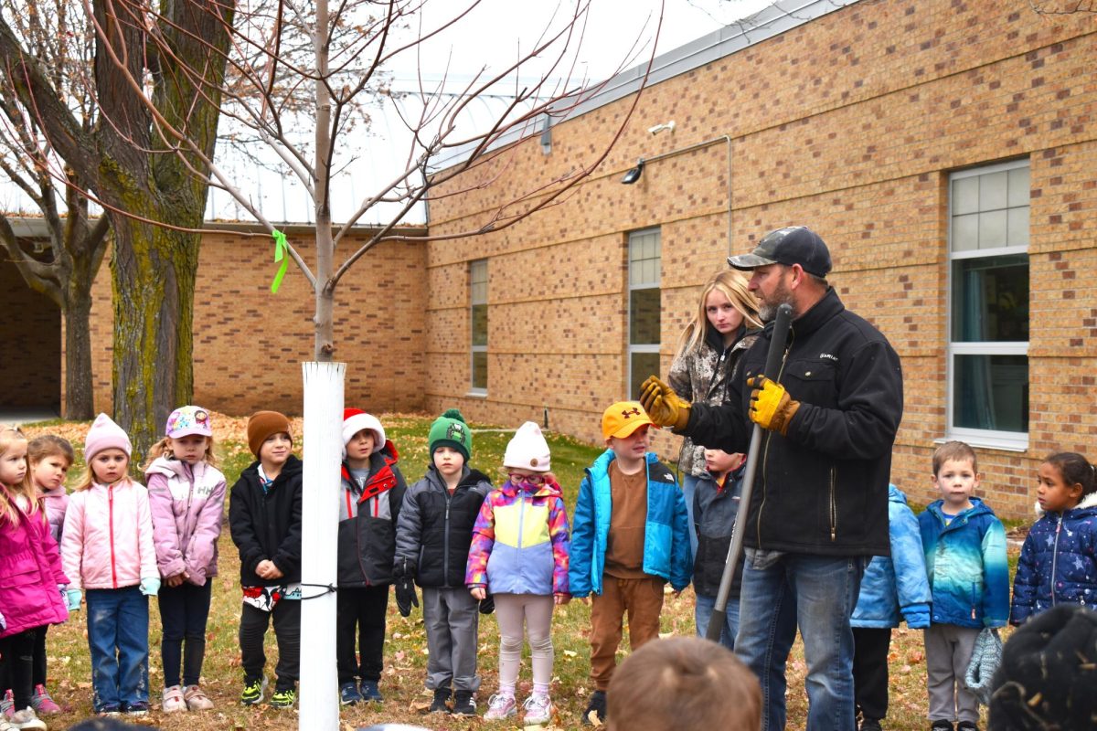 A member of the maintenance staff explains the tree replacement project to elementary students.