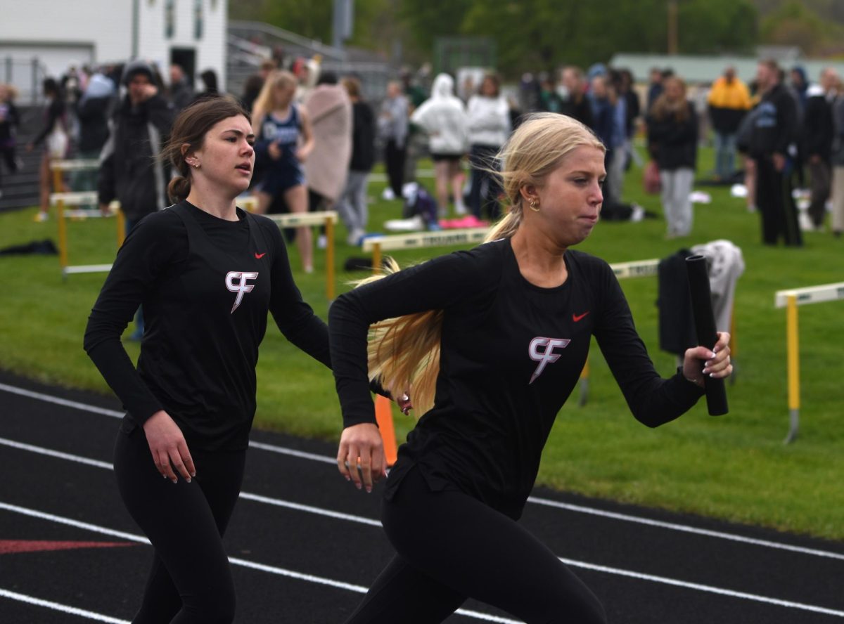 Lucy Lindahl (left) slows down after handing the baton to Rylann Miller (right) during the girls' 4x400 relay race at the True Team meet on May 5.